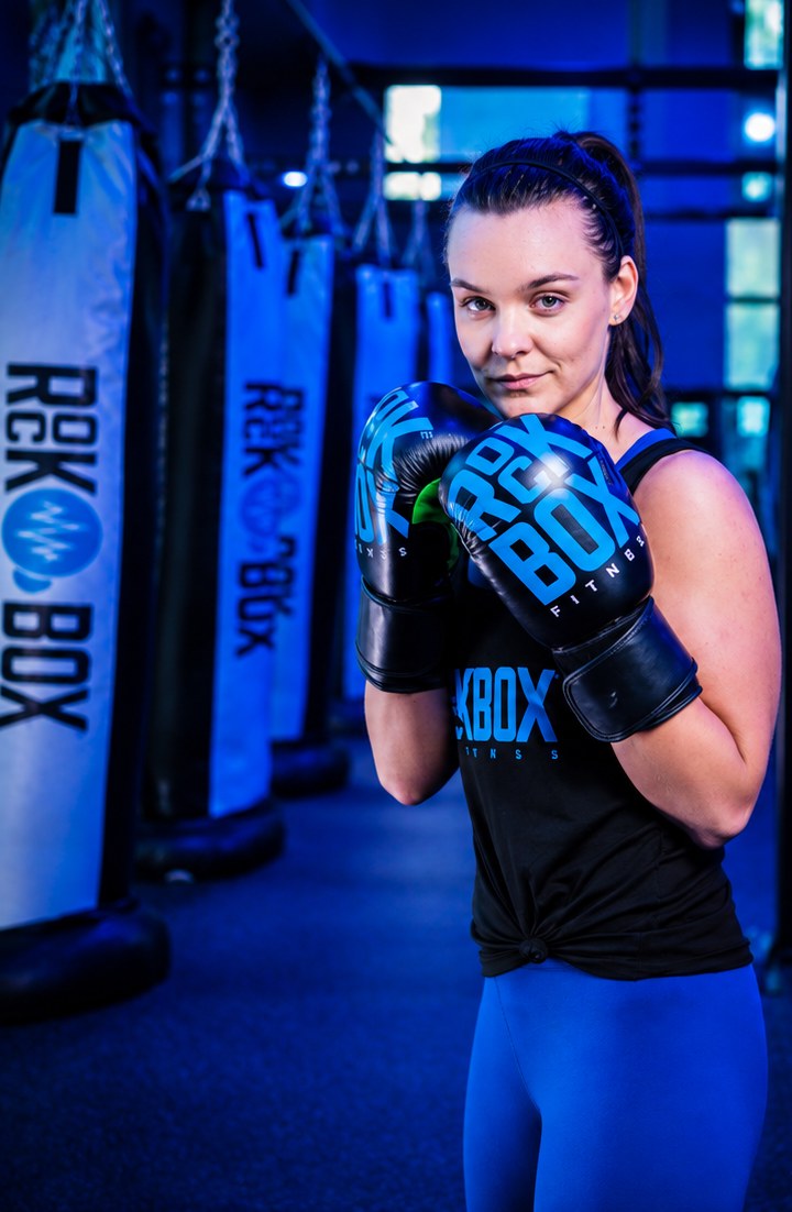 Rockbox member in gloves with guard up in front of the heavy bags